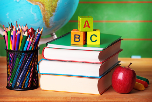 School books stacked up and colored pencils in a cup